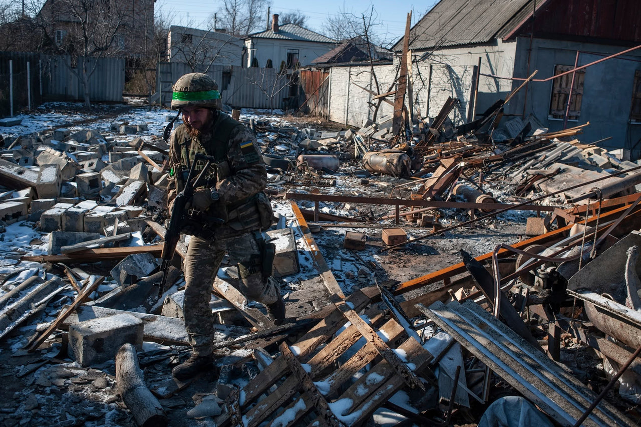 A servicemember moving through damaged buildings.
