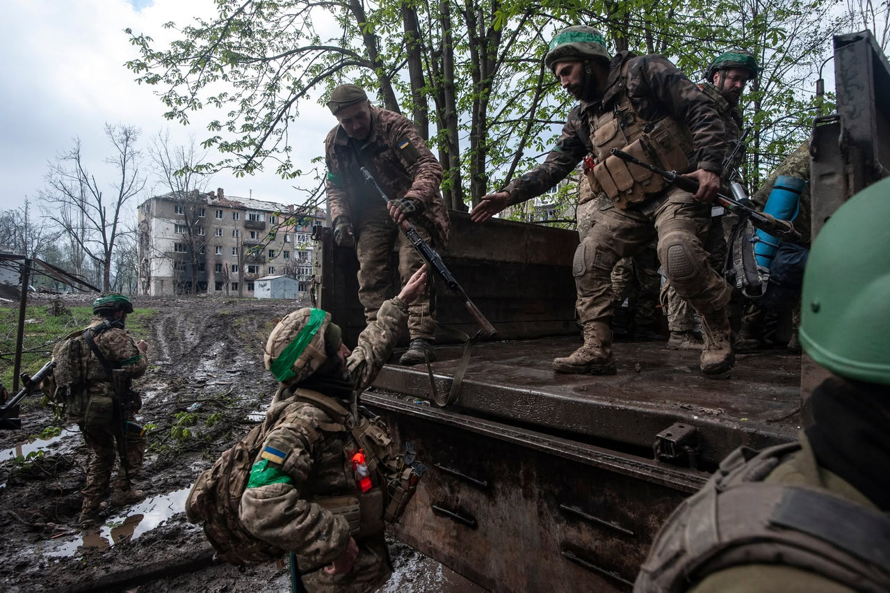 Servicemembers together beside a vehicle.